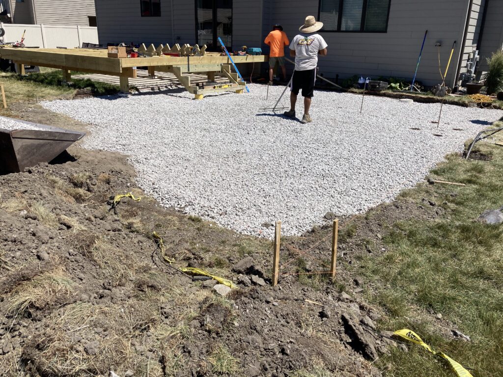 1. A man prepares a backyard patio with gravel, getting the site ready for artificial turf installation.
